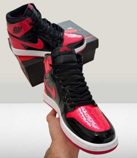 Close-up of Jordan 1 Patent-Bred's glossy red patent leather toe box and perforated detailing
